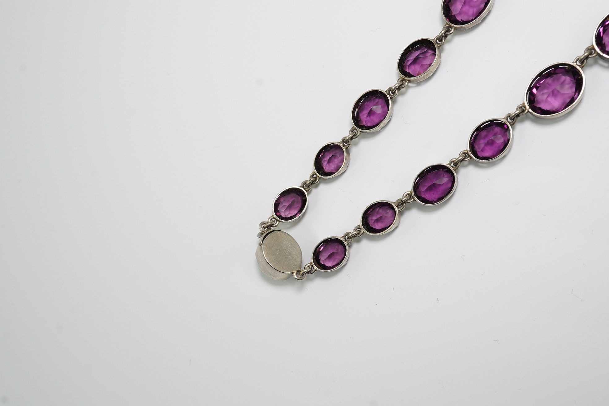 A Victorian silver and graduated oval cut amethyst paste set riviere necklace